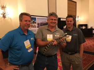 Holding a gator in front of the Ausley Trade Show Booth at Florida Educational Facilities Planners Association FEFPA Summer Conference in Boca Raton