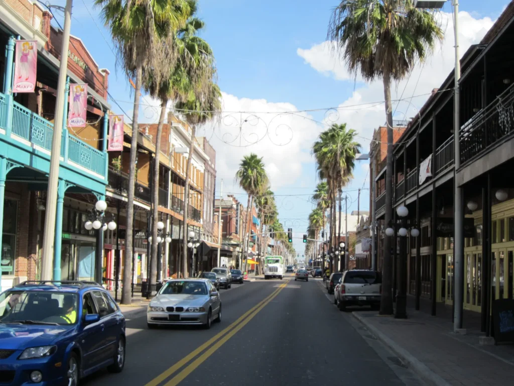 Palm-lined street with historic balconied buildings and parked cars