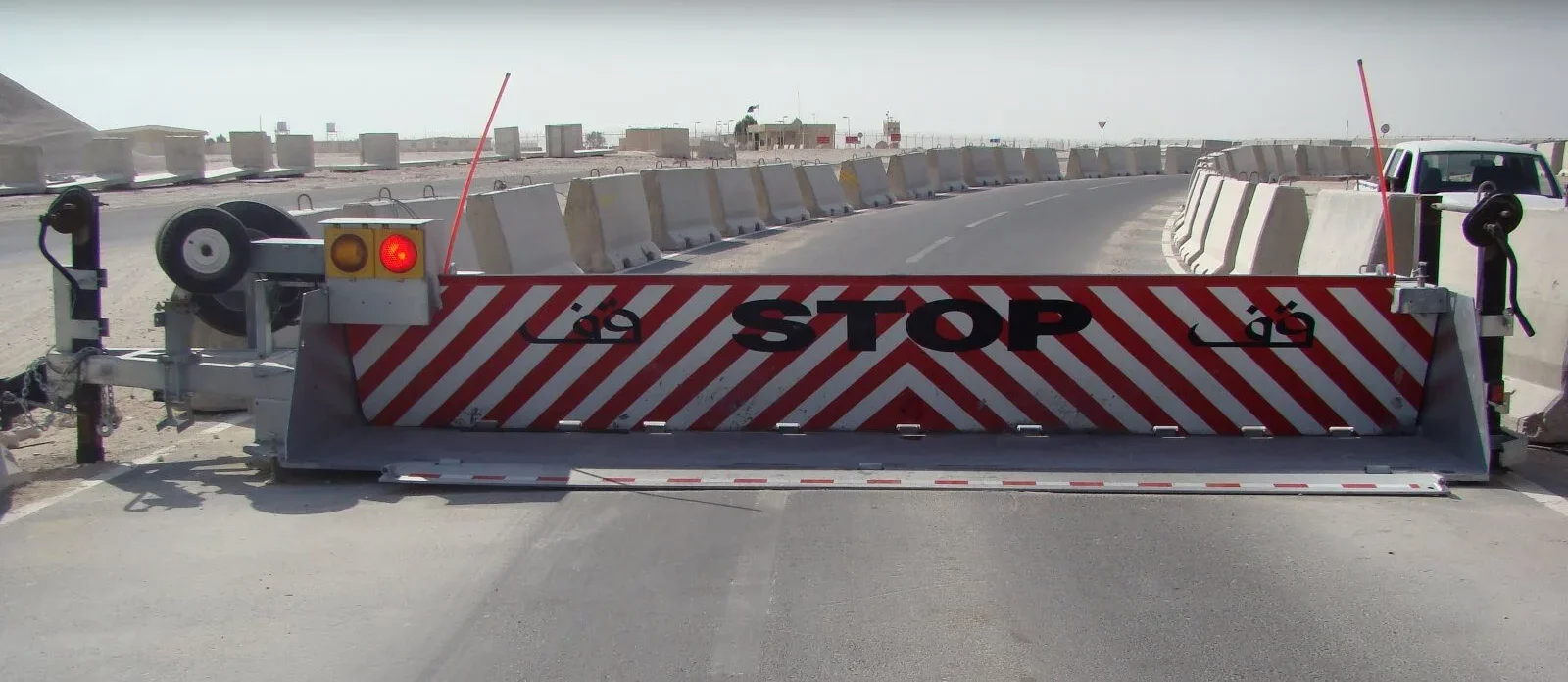 Mobile crash barrier with red and white STOP stripes on a paved area