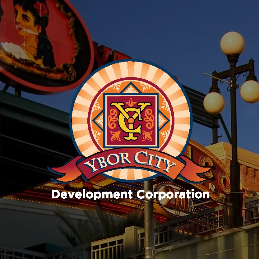 Ybor City Development Corporation logo over a street scene with lamps and a neon sign