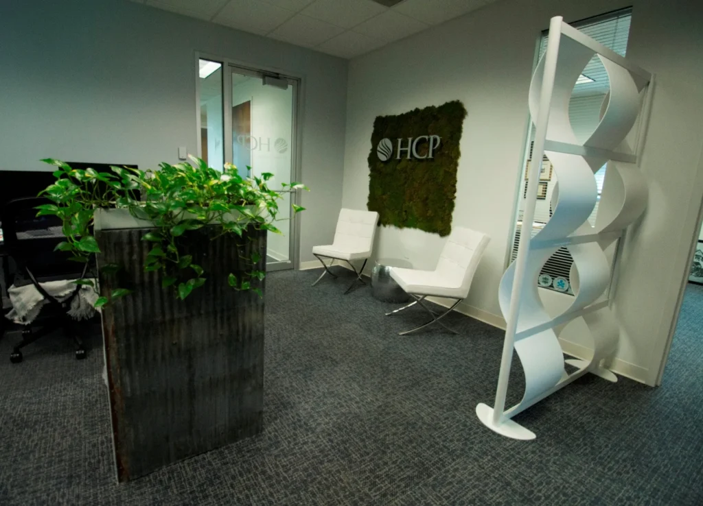 HCP Associates office reception area with white chairs, plants and a moss logo wall