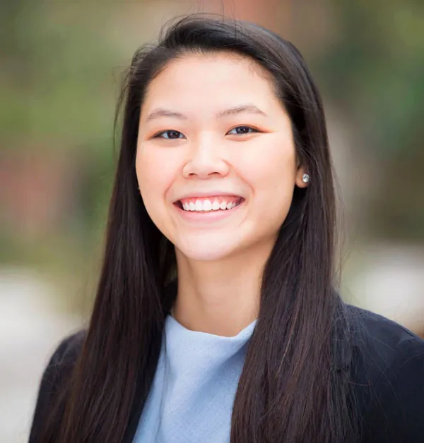 Smiling woman with long dark hair in a light blue top and black blazer