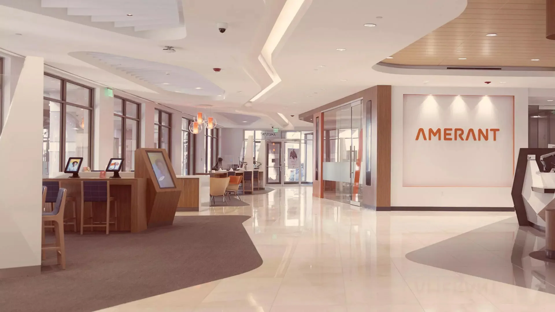 Spacious bank lobby with the Amerant name on the wall and kiosks near large windows