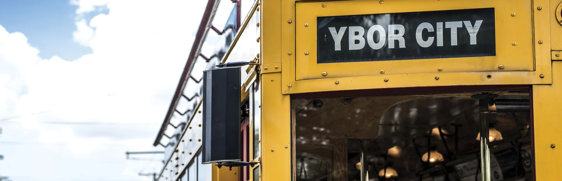 Yellow Ybor City streetcar with a street name sign under a blue sky
