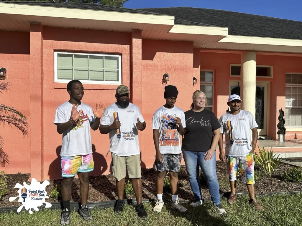 Volunteers posing in front of a coral colored house