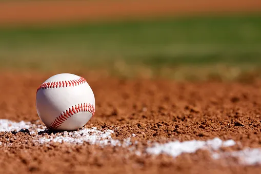 Baseball resting on the infield dirt beside the white chalk line