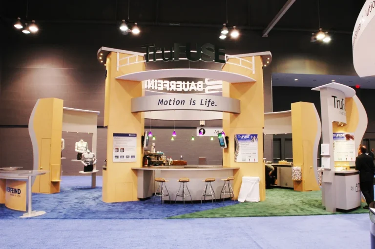 Tan two story trade show booth with curved wood panels and overhead sign