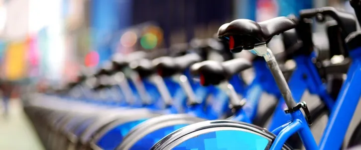 Row of blue bike share bicycles docked along a city street