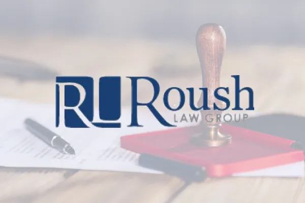 Roush Law Group logo over a photo of a desk with a notary stamp and pen