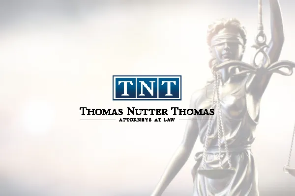 Thomas Nutter Thomas Attorneys at Law logo over a Lady Justice statue