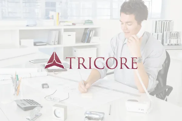 Tricore logo over a faded photo of a man on the phone at a desk