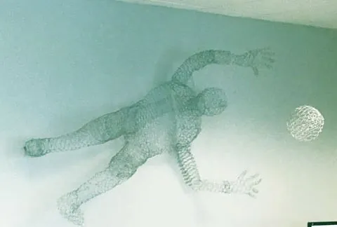 Wire mesh sculpture of a human figure stretched across a pale green wall