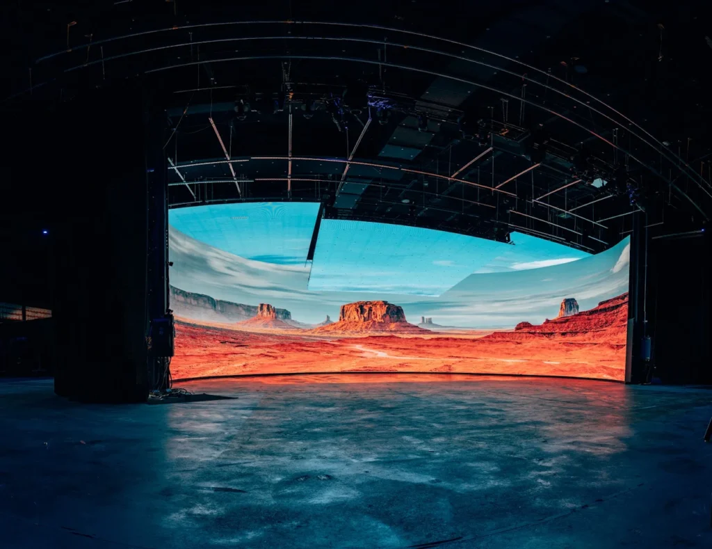 Virtual production studio with a curved LED wall showing a desert canyon landscape