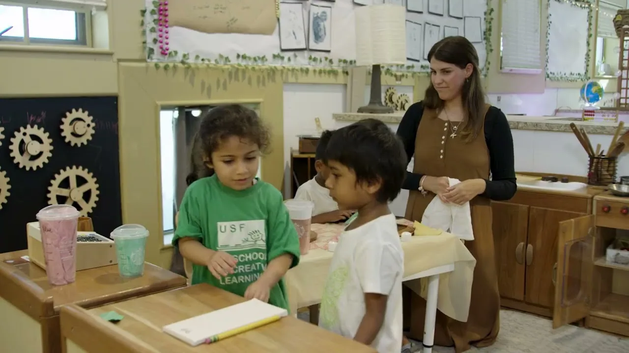 Teacher and two young children working at a table in a classroom