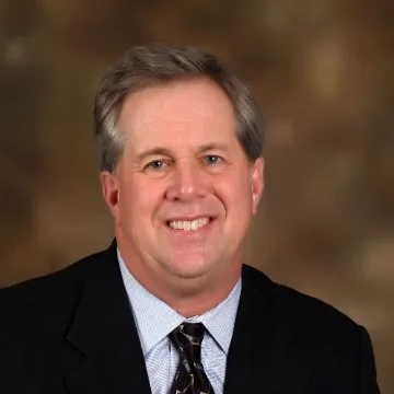 Smiling man with gray hair in a dark suit, striped shirt and tie