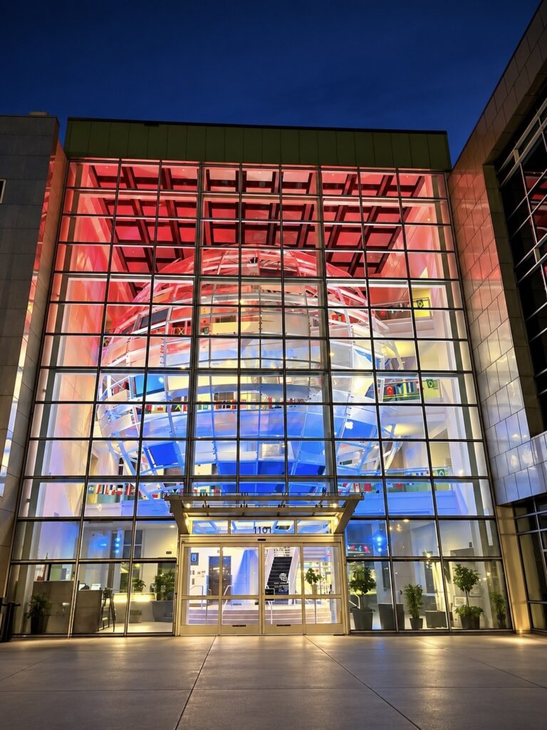Glass fronted building entrance lit in red and blue at night