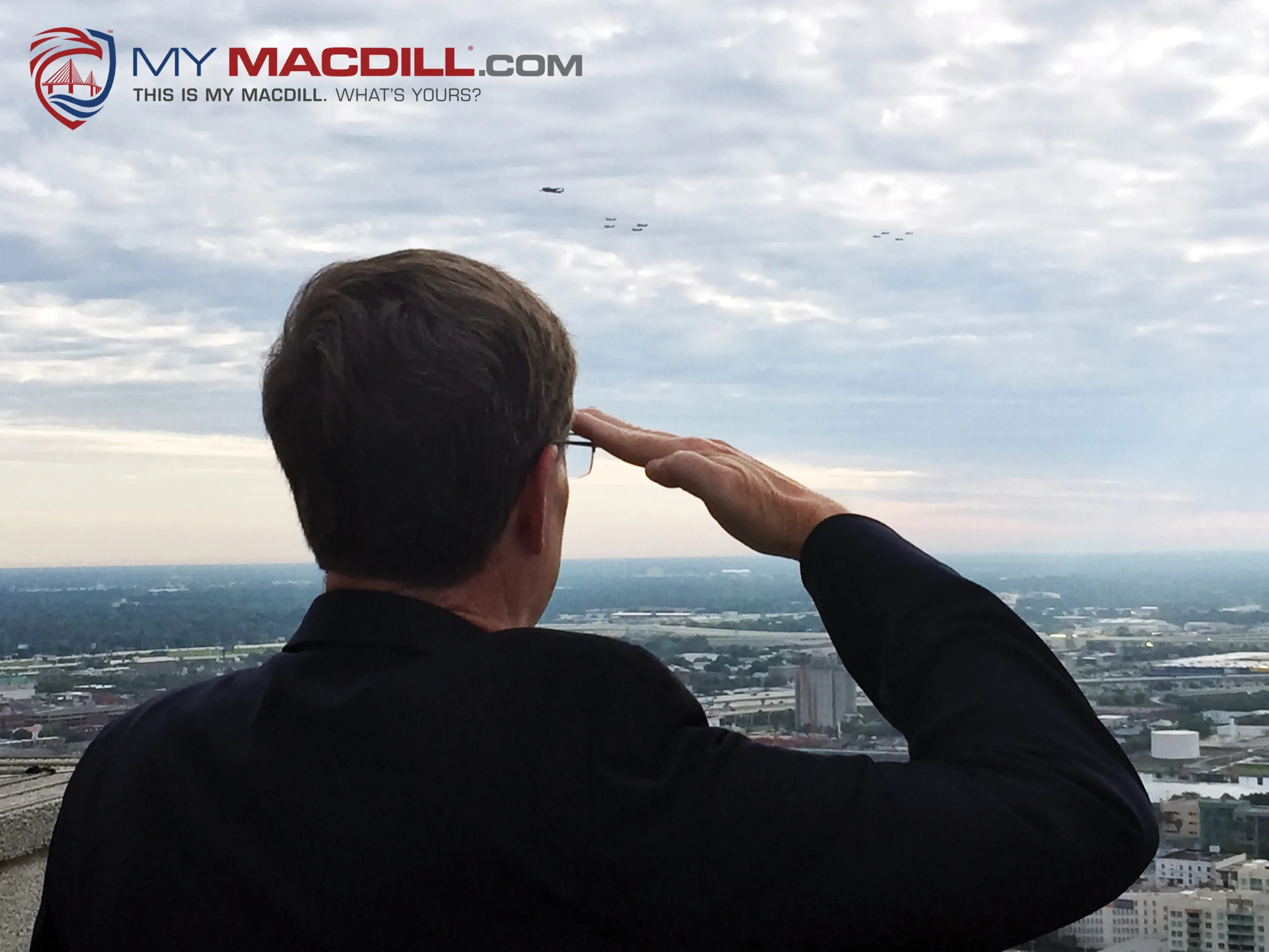 Man in a dark jacket saluting while looking out over Tampa skyline, My MacDill logo