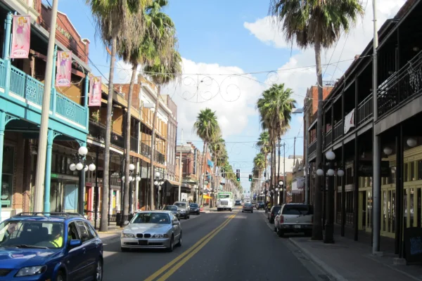 Palm-lined street with historic balconied buildings and parked cars