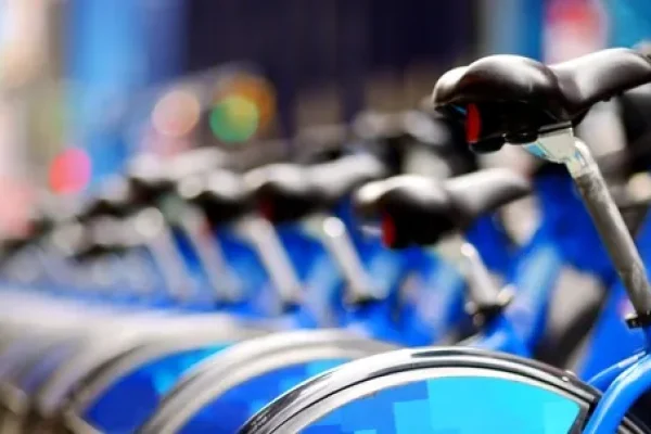 Row of blue bike share bicycles docked along a city street