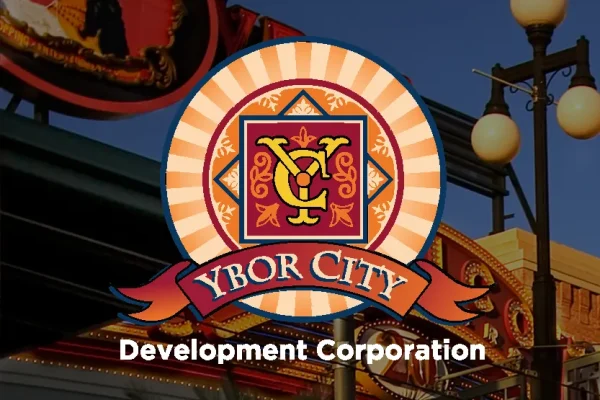 Ybor City Development Corporation logo over a street scene with lamps and a neon sign