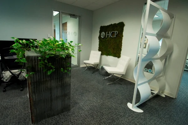 HCP Associates office reception area with white chairs, plants and a moss logo wall