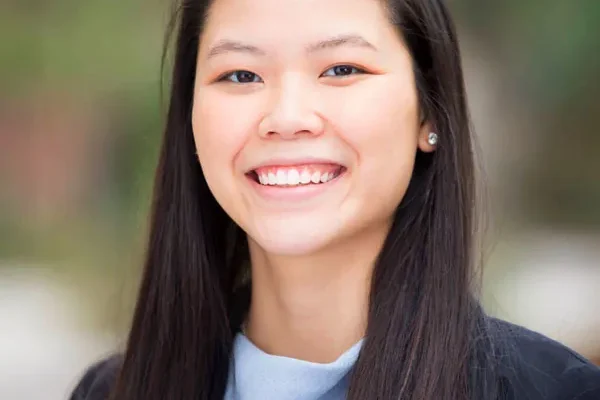 Smiling woman with long dark hair in a light blue top and black blazer