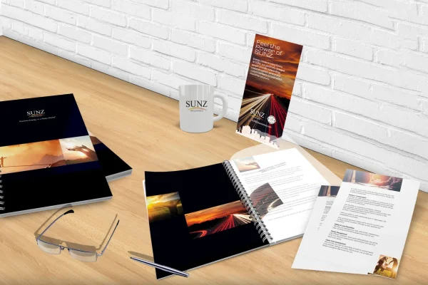 Sunz branded notebooks, mug, glasses and printed folder on a wooden surface