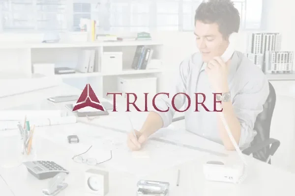 Tricore logo over a faded photo of a man on the phone at a desk