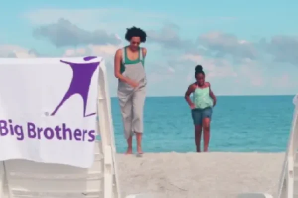 Big Brothers Big Sisters banner on a beach with two people in the back