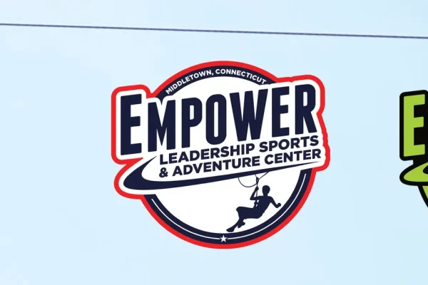 Zip line rider beside Empower Sports and Adventure Center and Empower Adventures logos