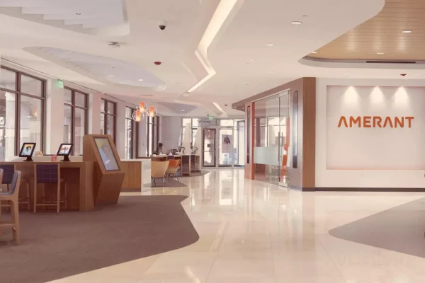 Spacious bank lobby with the Amerant name on the wall and kiosks near large windows