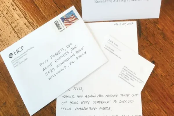Handwritten thank you note, envelope, and HCP note card on a wooden desk